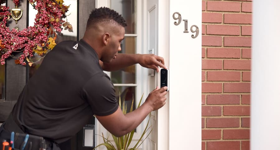 Vivint team member installing a doorbell camera on the outside of a home
